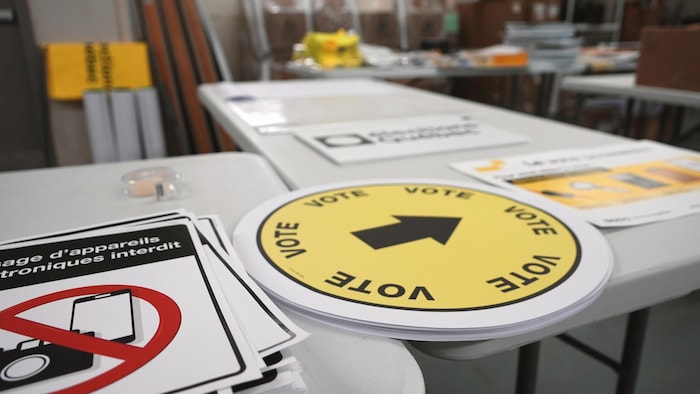 Une pile d'autocollants sur une table, jaunes avec une flèche et le mot «Vote».