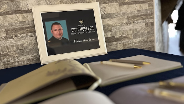 Une photo du sergent Eric Mueller, devant deux livres de condoléances à signer.