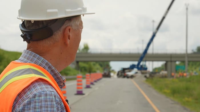 Un ingénieur regardant un pont à étagement en rénovation, en été.