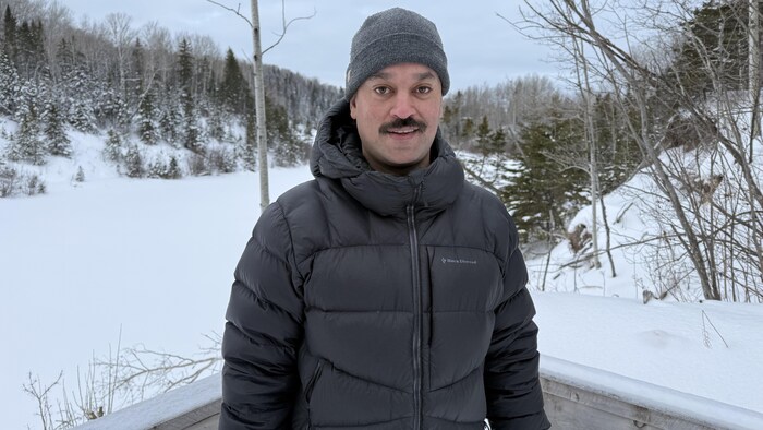 Un homme moustachu sourit à la caméra.