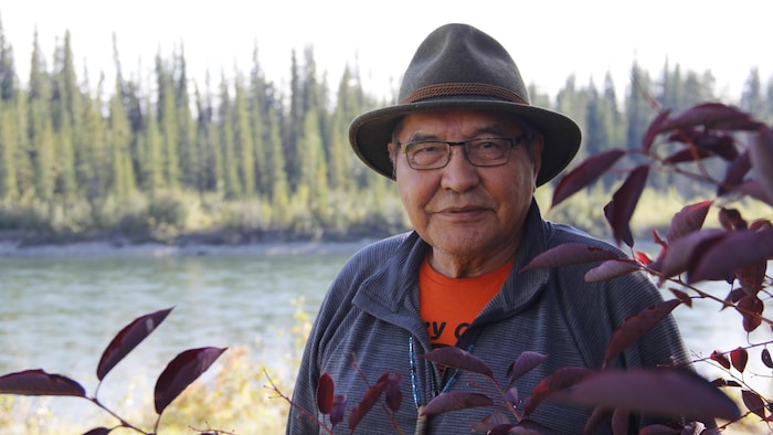 Un homme portant un chapeau au bord d'une rivière.