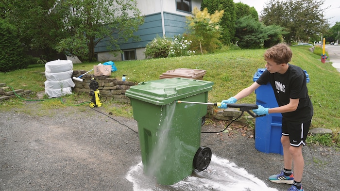 Un jeune lave un bac vert.