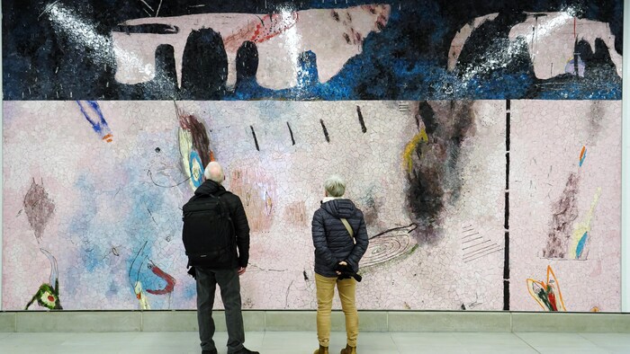 Deux personnes regardent une œuvre.