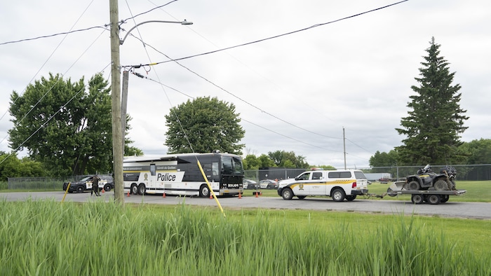 Un poste de commandement de la SQ est établi dans une rue aux abords d'un champ.