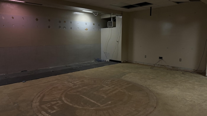 Une pièce vide avec en lad   centre une hint  du logo des Remparts au sol.