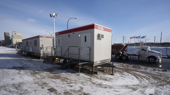 Deux roulottes sont installées sur un terrain qui longe une rue passante.