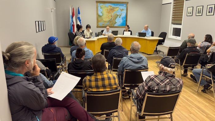 Citoyens assis dans la salle écoutent attentivement les explications des élus.