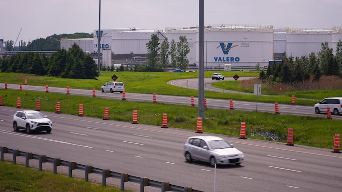 Des autos circulent sur l'autoroute devant les réservoirs de Valero.