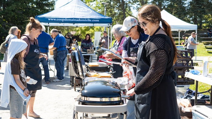 Des personnes participent au barbecue au parc Beauséjour à Rimouski.