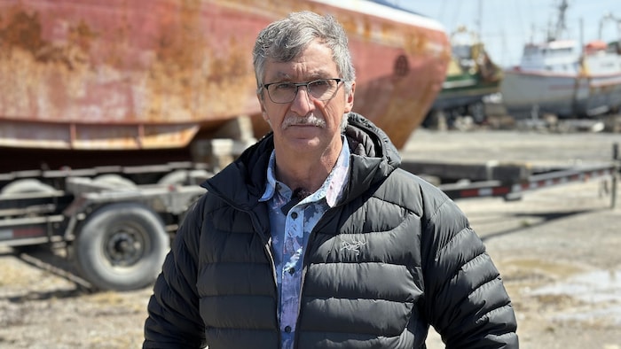 Pierre-Marc Dufresne pose à la caméra devant un bateau.