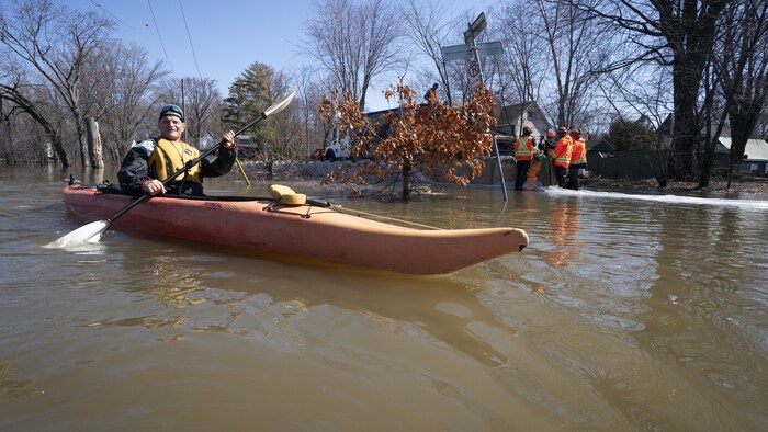 Un kayakiste sur une rue inondée.