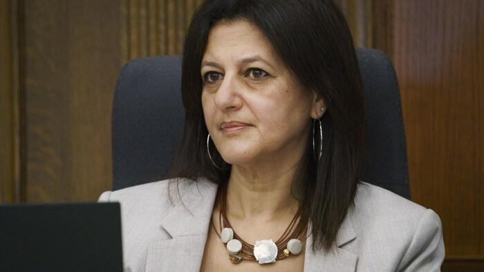 Une femme assise dans une salle d'un palais de Justice.