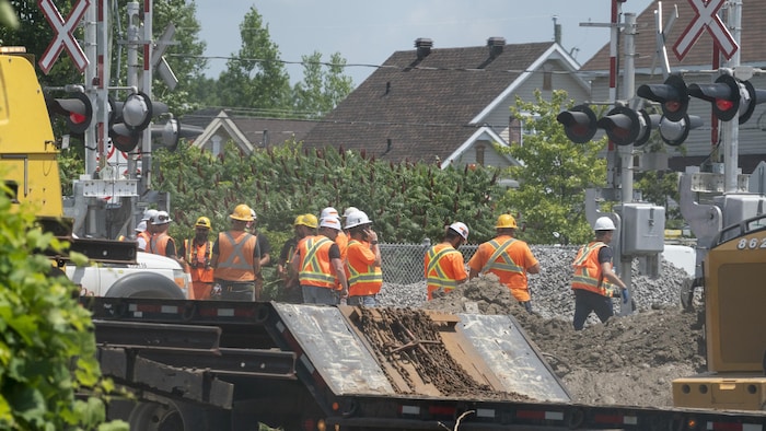 Des travailleurs en habit de construction proche d'un chemin de fer.