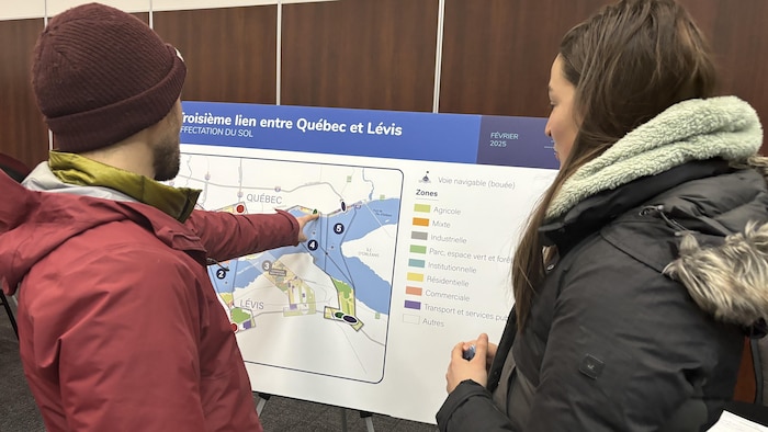 Deux personnes regardent une affiche devant un kiosque.