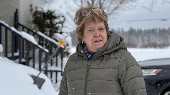 Portrait de la dame âgée d'une soixantaine d'année devant chez elle en hiver.