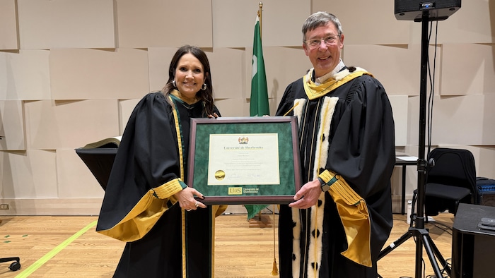 Une femme et un homme qui tiennent un cadre contenant un diplôme.