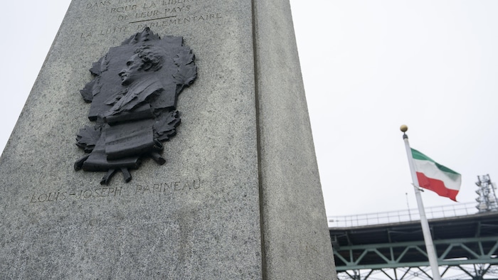 Le monument devant le pont et un drapeau des patriotes.