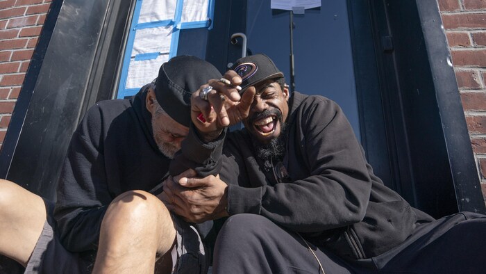 Joaquin Dawes et James Malone, assis, rient côte à côte.