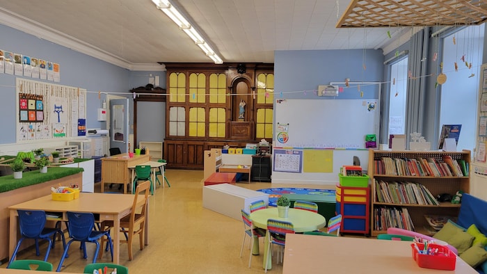 Une salle de classe avec des tables et de petites chaises.
