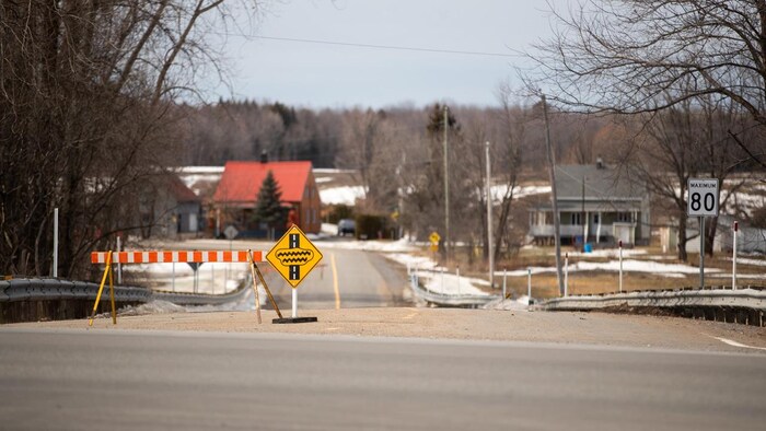 Des pancartes de rue fermée et d’inondations bloquent l’accès à une rue.