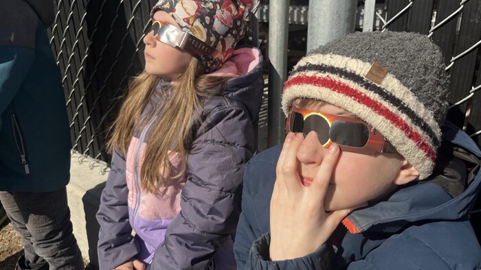 Deux enfants regardent le ciel avec des lunettes de protection. 
