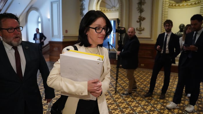 Sonia LeBel portant un cartable de documents dans un couloir de l'Assemblée nationale.