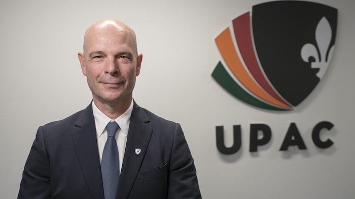 Vincent Richer pose à côté du logo de l'UPAC.