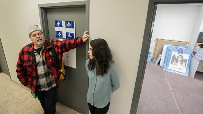 Louis Champagne, debout à côté de Rose Lessard, discute dans un corridor.
