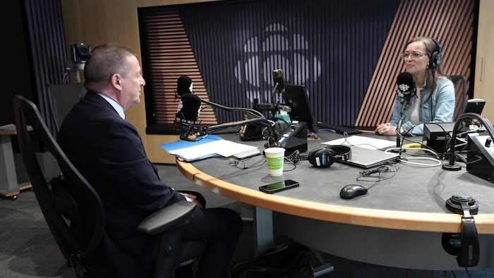 Luc Monty parle avec la journaliste dans un studio de radio.