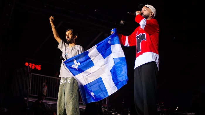 Deux chanteurs et le drapeau du Québec.