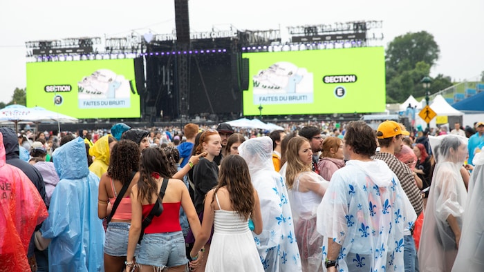 Des festivaliers sont sur les plaines d'Abraham, sous la pluie.