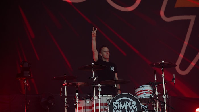 Le batteur, derrière son instrument, lève le bras.