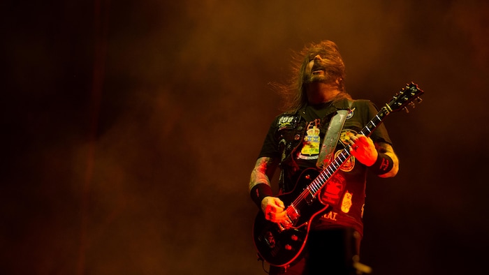 Gary Holt joue de la guitare en secouant la tête.