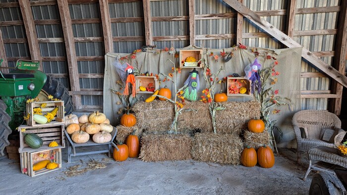 Un présentoir avec des décorations d'halloween, des balles de foin, des courges et des citrouilles. 