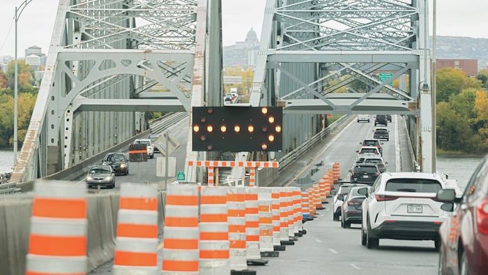 Des véhicules en file dans le trafic en entrant sur un pont avec, dans le décor, le mont Royal et l'oratoire Saint-Joseph.