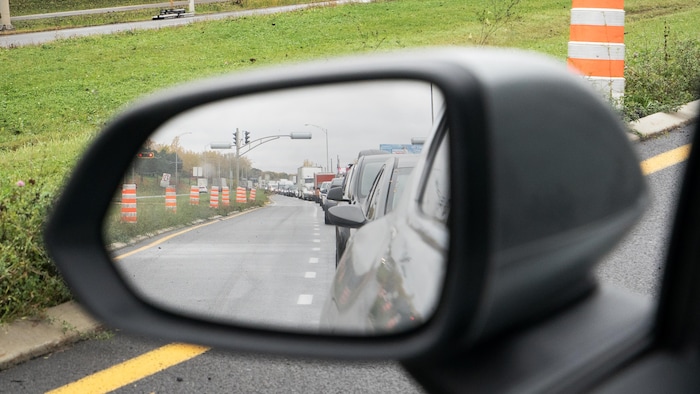 Des véhicules en file dans le trafic en entrant sur un pont avec, dans le décor, le mont Royal et l'oratoire Saint-Joseph.