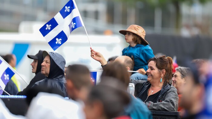 Un enfant a un drapeau dans les mains sur les épaules de ses parents. 