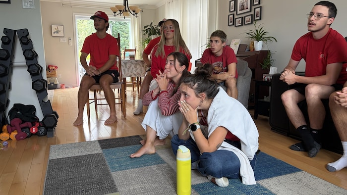 Un groupe regarde la télévision, visiblement nerveux.