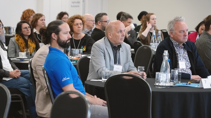 Des participants écoutent la personne qui parle au micro.