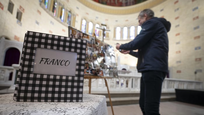 Une personne rend hommage à Franco Nuovo pendant ses funérailles dans une église.
