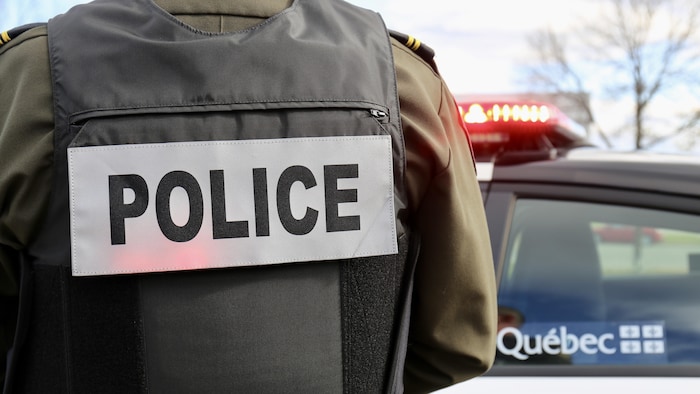 Un policier devant une voiture.