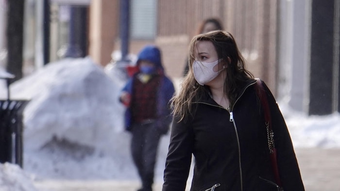 Gens dans la rue le visage couvert par un masque.