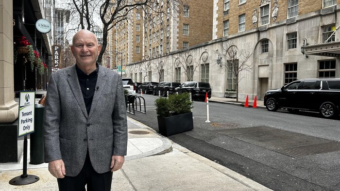 Gilles Thériault, debout sur un trottoir, dans une ville.