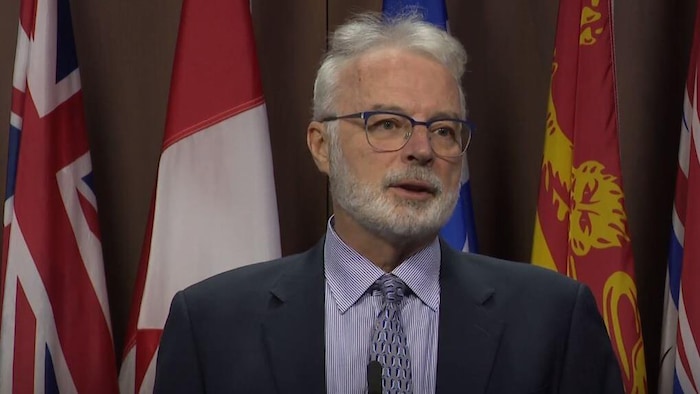 Un homme portant des lunettes (Robert McCorquodale) lors d'une conférence de presse à Ottawa.