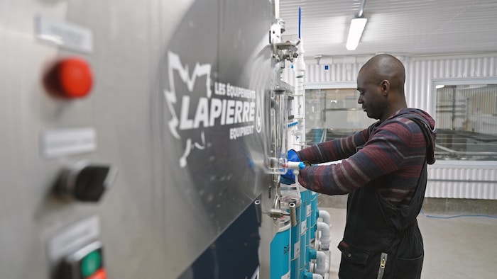 Hardy Luyeye devant une machine pour traiter l'eau d'érable. 