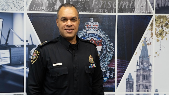 Peter Sloly pose devant le logo du Service de police d'Ottawa.