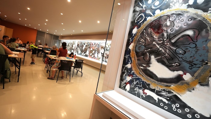 La fresque couvre tout un côté du mur d'un couloir où se trouvent des tables et des bancs placés pour les visiteurs. 