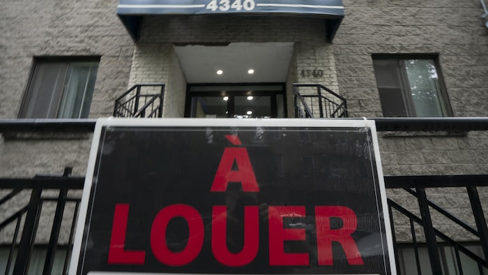 Une affiche «à louer» devant un immeuble.