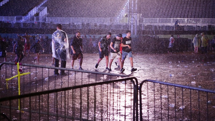 Des festivaliers marchent sous la pluie. 