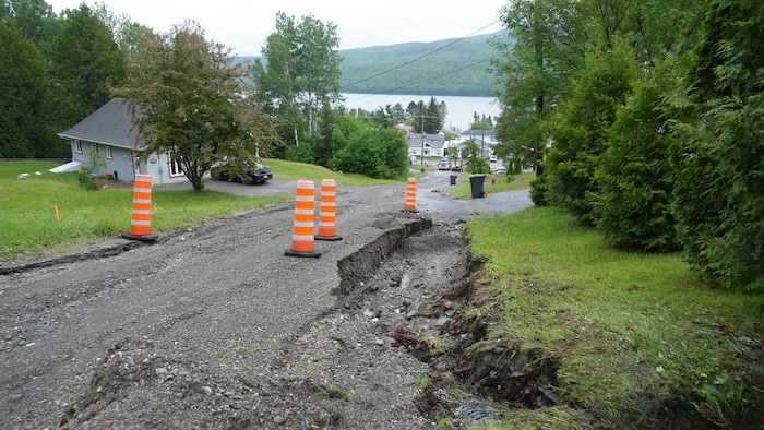 Des cônes le long d'une rue résidentielle défoncée.